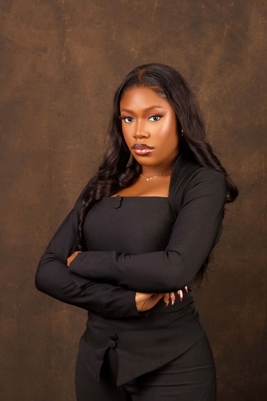 Portrait of a confident woman in black on a warm brown backdrop, representing Toni Purry's author presence.